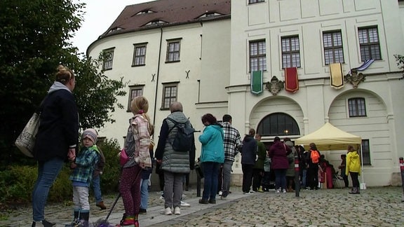 Menschen stehen vor dem Schloss Hoyerswerda in einer Schlange