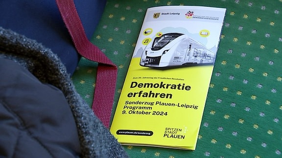 Ein Faltblatt mit der Aufschrift "Demokratie erfahren" liegt auf einem Sitz. 