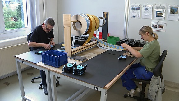 Ein Mann und eine Frau sitzen an einem Tisch und arbeiten.