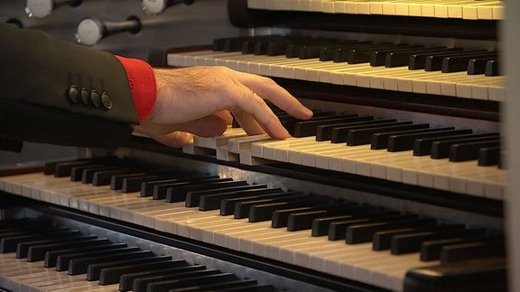 Hände bedienen die Klaviatur der Porsche-Orgel