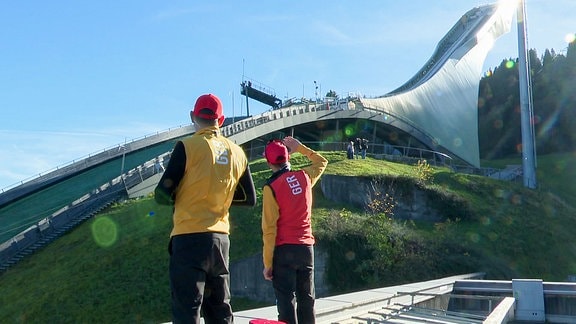 Zwei Männer schauen auf eine Skisprungschanze