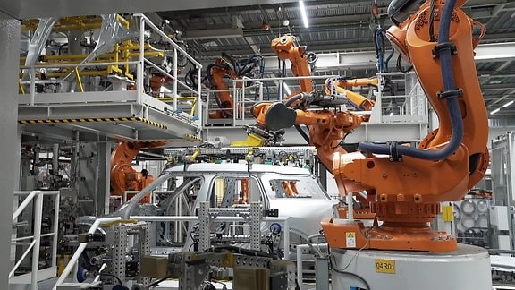 In einer Autofabrik setzt ein Robotorarm ein Auto zusammen.