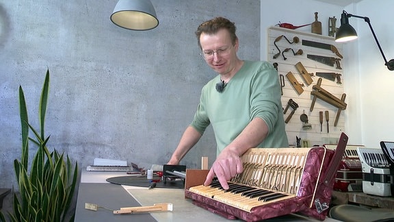 Ein Instrumentenbauer zeigt auf ein Akkordeon.
