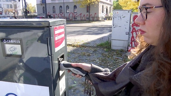 Eine Frau betrachtet eine angeschlossene Ladesäule