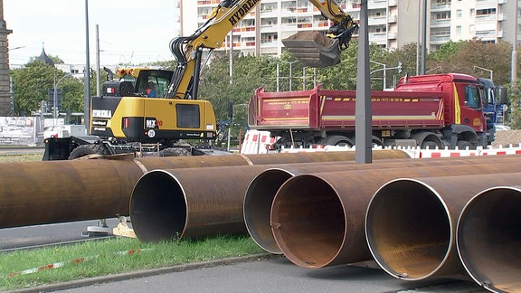 Ein Bagger und ein LKW vor Stahlröhren