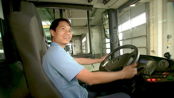 Ein Busfahrer lächelt in seinem Fahrzeug