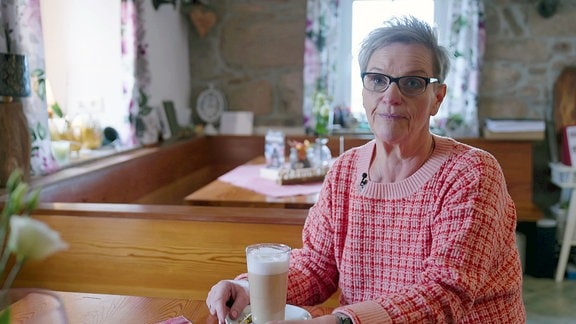 Eine Frau sitzt bei einem Kaffee am Tisch einer Gaststube