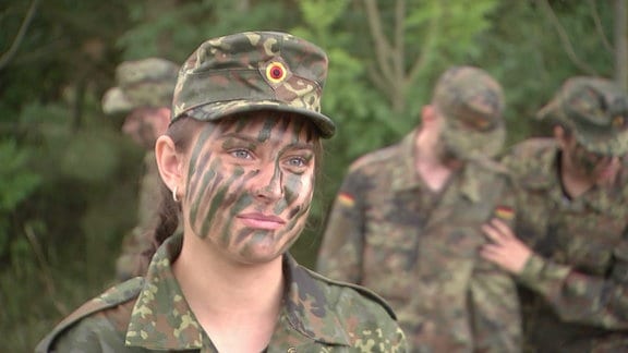 Eine Schülerin als Soldatin in Tarnkleidung