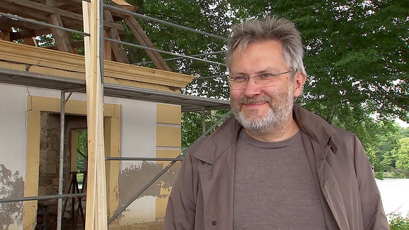 Ein Mann vor einem eingerüsteten Nebengebäude des Moritzburger Schlosses im Interview