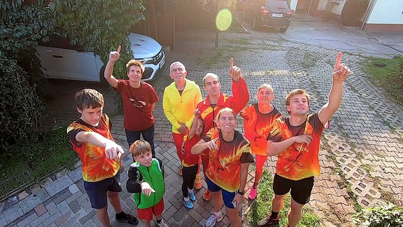 Eine Familie in roter Sportkleidung zeigt nach oben.