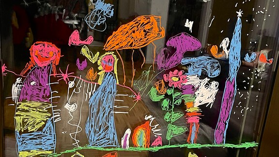 Ein Kinderzeichnung auf einer Fensterzeichnung mit Kindern, Blumen und Schmetterlingen