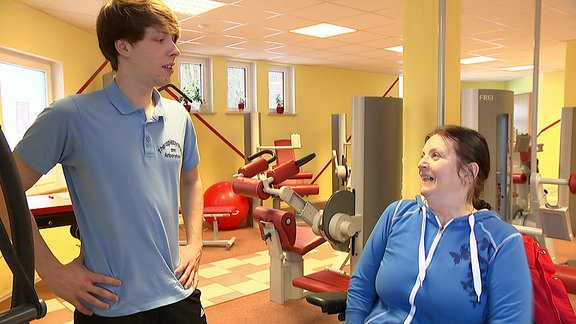 Eine Frau in einem Fitness-Studio, neben ihr ein junger Mann