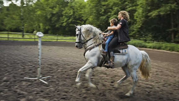 Ein Junge und ein Mann auf einem Pferd