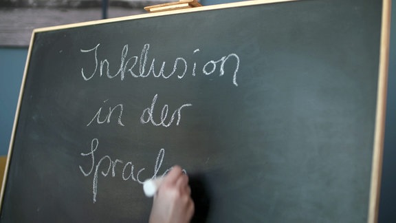 ''Inklusion in der Sprache'' wird an eine Tafel geschrieben.