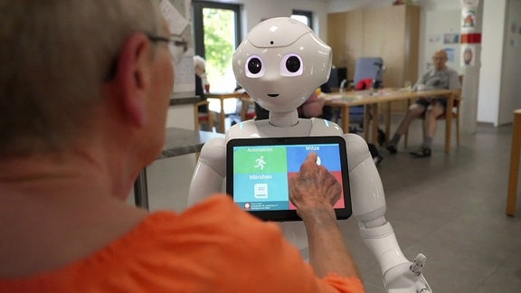 Ein Frau bedient ein iPad an einem Roboter