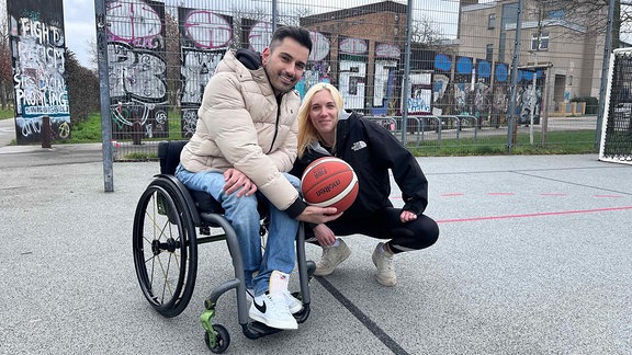 Mann im Rollstuhl mit Basketball, daneben eine blonde Frau