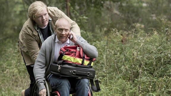 Der Landarzt Dr. Chris Wegner (Simon Schwarz) im Rollstuhl und Finn (Sebastian Griegel), der Sohn des vermissten Bankchefs.