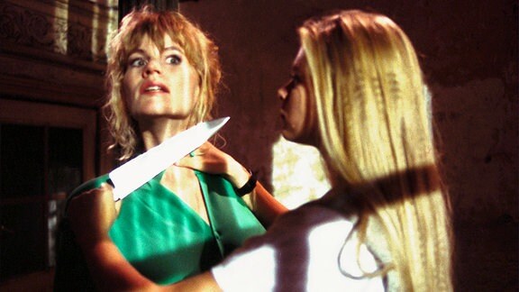 Barbara (Anne Kasprik, li.) wird von Melanie (Anne-Sophie Briest) mit einem Messer bedroht.