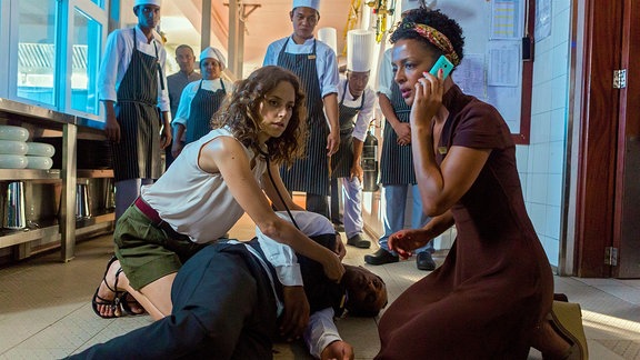 Einsatz für Filipa (Anja Knauer): Der Kellner Jimmy (Selam Tadese) ist zusammengebrochen. Stella (Dennenesch Zoudé) ruft den Rettungswagen.