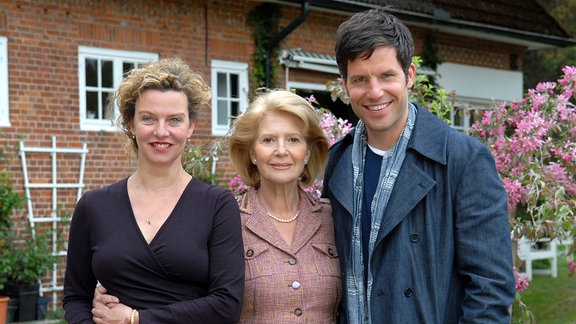 Luise (Christiane Hörbiger, Mitte) neben ihren beiden Kindern Daniel (Tim Bergmann) und Charlotte (Margarita Broich) in einem Garten stehend.