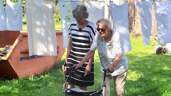 Leonore Pengel mit Rollator (rechts) geht mit ihrer Tochter durch den Garten . 
