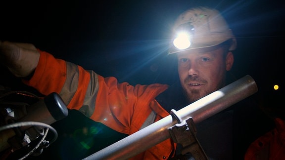 Paul Klinger mit Helm und Stirnlampe in der Dunkelheit bei der Arbeit.