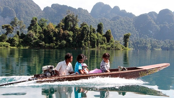 Eine Fischerfamilie fährt über den Khao-Sok-See zu einer religiösen Zeremonie in den Wald.