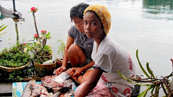 Die Töchter der Fischerfamilien am thailändischen Khao-Sok-See nehmen den Fang aus.