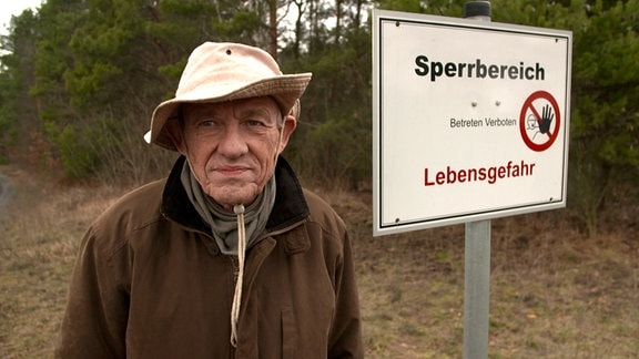Holger Gehm neben einem Schild mit der Aufschrift:"Sperrbereich. Betreten verboten! Lebensgefahr"