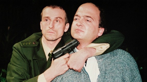 Pelitz (André Hennicke, li.) hält Dörner (Florian Martens/r.) eine Pistole an den Hals.