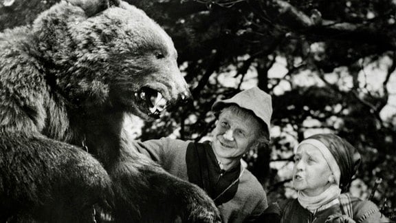Eine alte Frau und ein alter Mann mit einem angeketteten Bären.