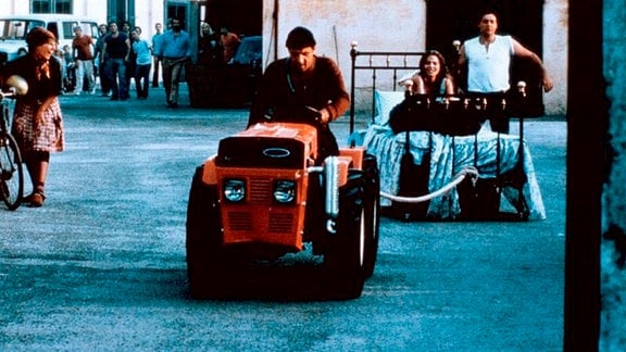 Elia (Adriano Celentano, l.) schreckt nicht davor zurück, die wütend protestierende Lisa (Ornella Muti) durchs Dorf zu ziehen.