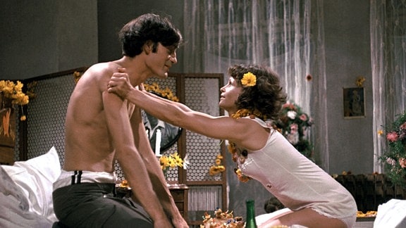Szene aus dem DEFA-Film "Die Legende von Paul und Paula": Paul (Winfried Glatzeder) und Paula (Angelica Domröse) in Paulas geschmücktem Bett.