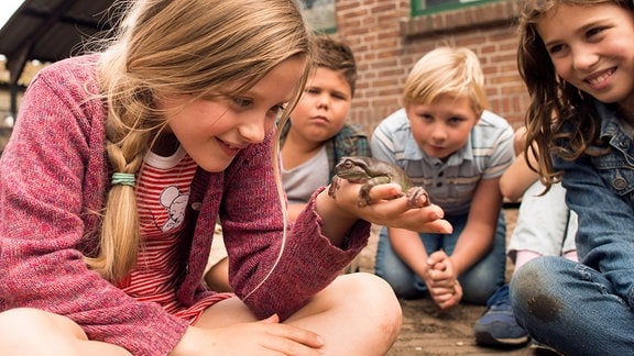 Sita (Yenthe Bos, vorn) hat herausgefunden, dass ihr Lehrer Frans sich in einen Frosch verwandeln kann. Da staunen auch ihre Mitschüler.