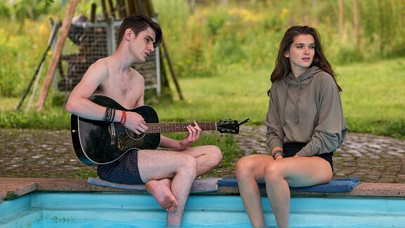 Tori (Caroline Hartig) und Philipp (Nikolas Weber) musizieren am Pool.