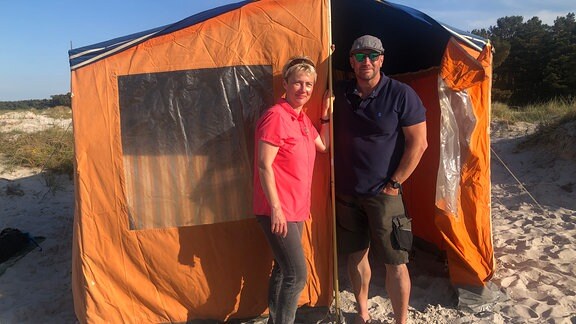 Christiane und Mathias Reinäcker stehen vor einem Zelt am Prerower Strand. 