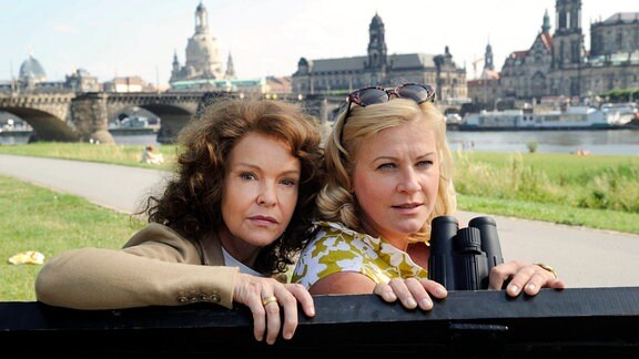 Thea (Katrin Sass) und Babette (Petra Kleinert, re.) sitzen auf einer Bank auf dem rechten Dresdner Elbufer - im Hintergrund die markante Kulisse der Dresdner Barockbauten.