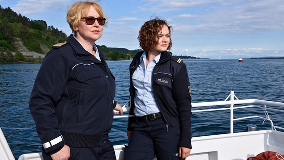 Zwei Frauen in Polizeiuniform sind an Bord eines Schiffes. Im Hintergrund ist der Bodensee zu sehen.