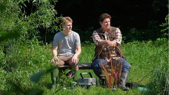 Zwei Männer sitzen auf einer Bank.