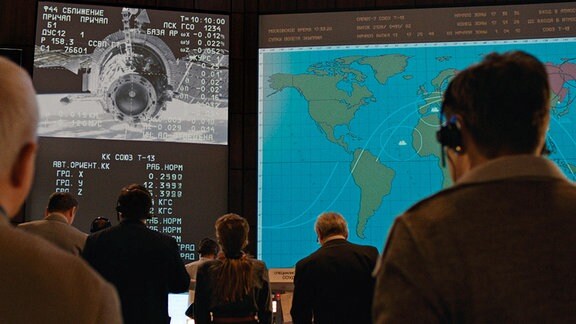 Russische Mitarbeiter blicken im Kontrollzentrum auf einen Bildschirm.