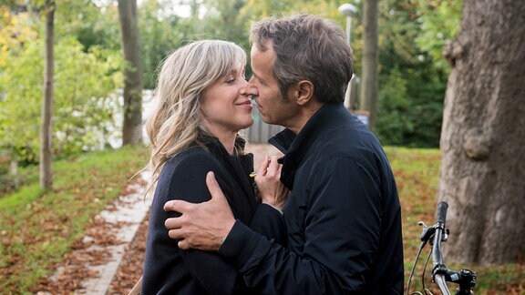 Florian (r.) küsst Katrin (l.) im Park.