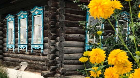 Blumen vor einem sibirischen Holzhaus