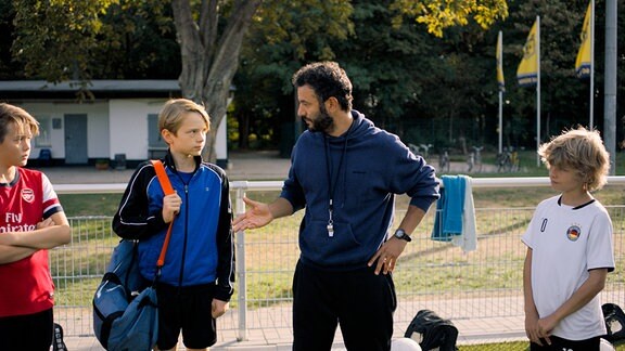 Trainer Rainer (Mohamed Achour) stellt Ben (Yoran Leicher) der Mannschaft des SC Düren vor.
