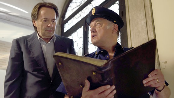Sergente Vianello (Karl Fischer) zeigt Commissario Brunetti (Uwe Kockisch, li.) die fehlenden Buchseiten.