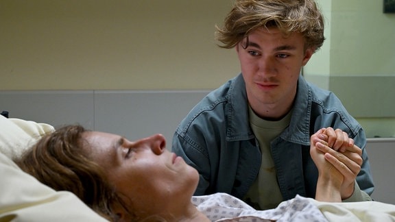 Aaron sitzt am Krankenbett seiner Mutter Karin.