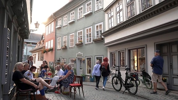 Menschen sitzen in einem Café auf der Krämerbrücke in Erfurt.