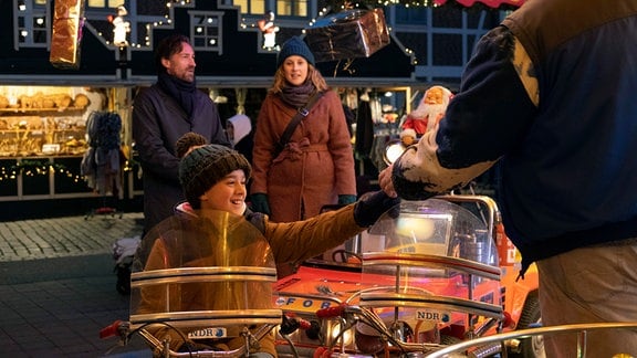 Tom (Benjamin Sadler) verbringt mit Sarah (Marlene Morreis) und ihrem Sohn Paul (Oskar Netzel) Zeit auf dem Weihnachtsmarkt