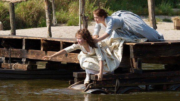 Die Schwestern (Hannah Herzsprung und Henriette Confurius, r) versuchen Schiller aus dem Wasser zu ziehen, der ein ertrinkendes Mädchen aus der Saale rettet.