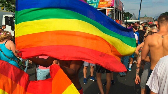 Ein Mann schwingt eine Regenbogenflagge auf dem gay pride Festival in Berlin.
