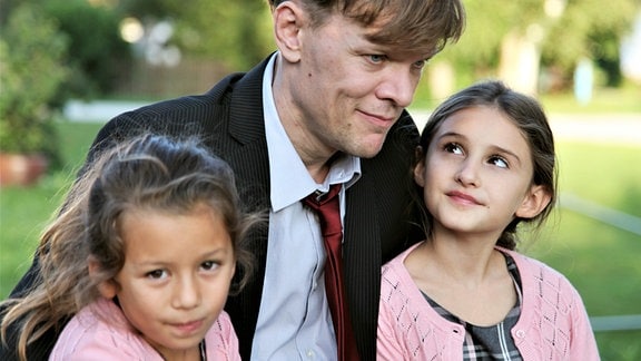 Der alleinerziehenden Willi Schulz (Sebastian Hülk) mit seinen Töchtern Lisa (Arwen Hollweg, re.) und Maria (Alice Azem).